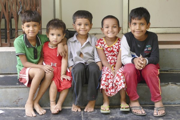 Five smiling children sitting together on a step